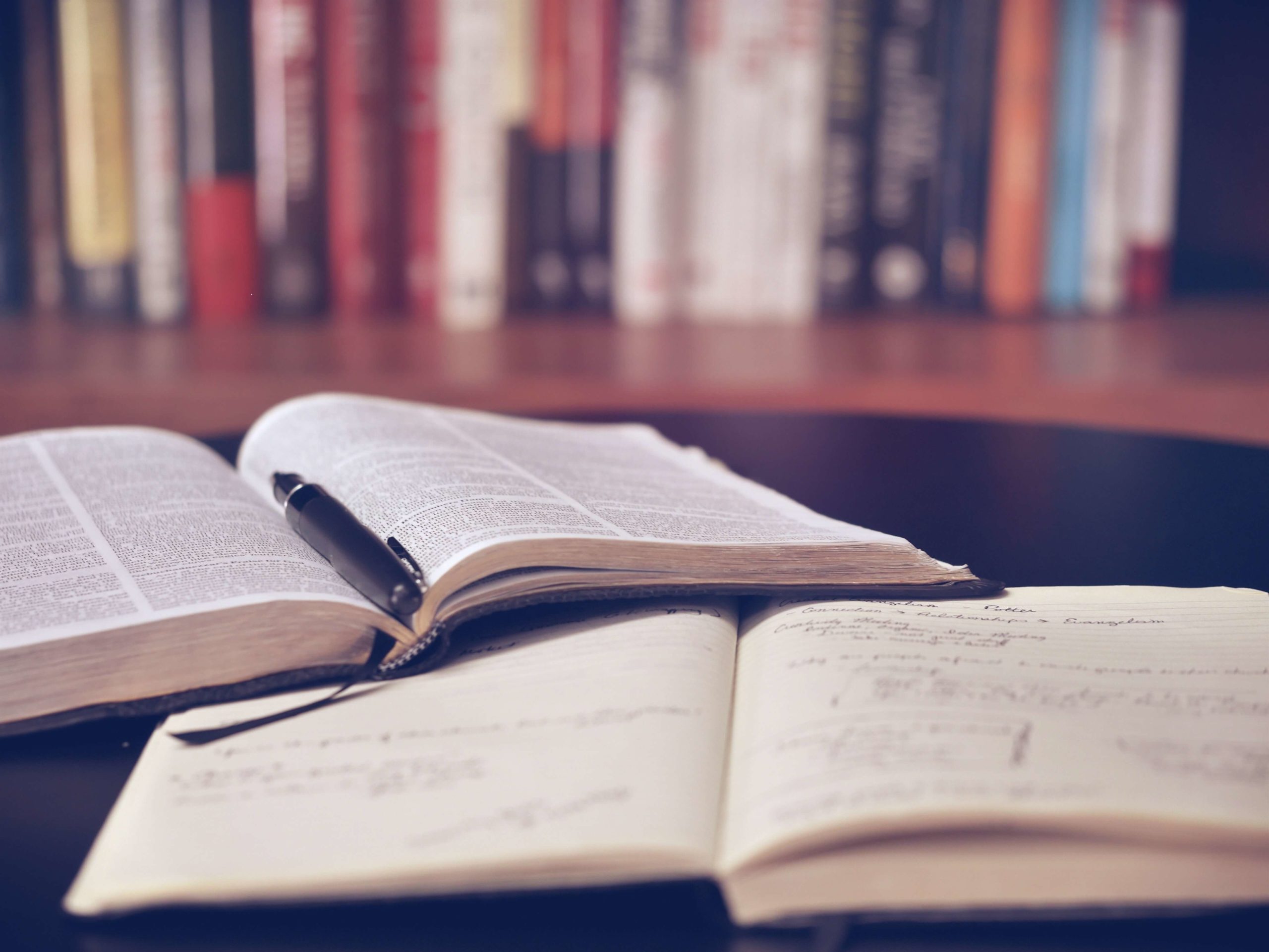 open bible on top of a notebook in a library